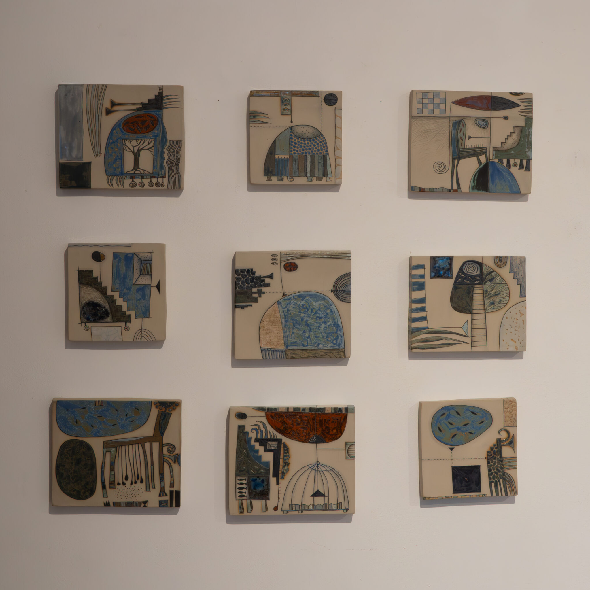 Üheksa abstraktse kujundusega keraamilist seinaplaati ruudustikus.