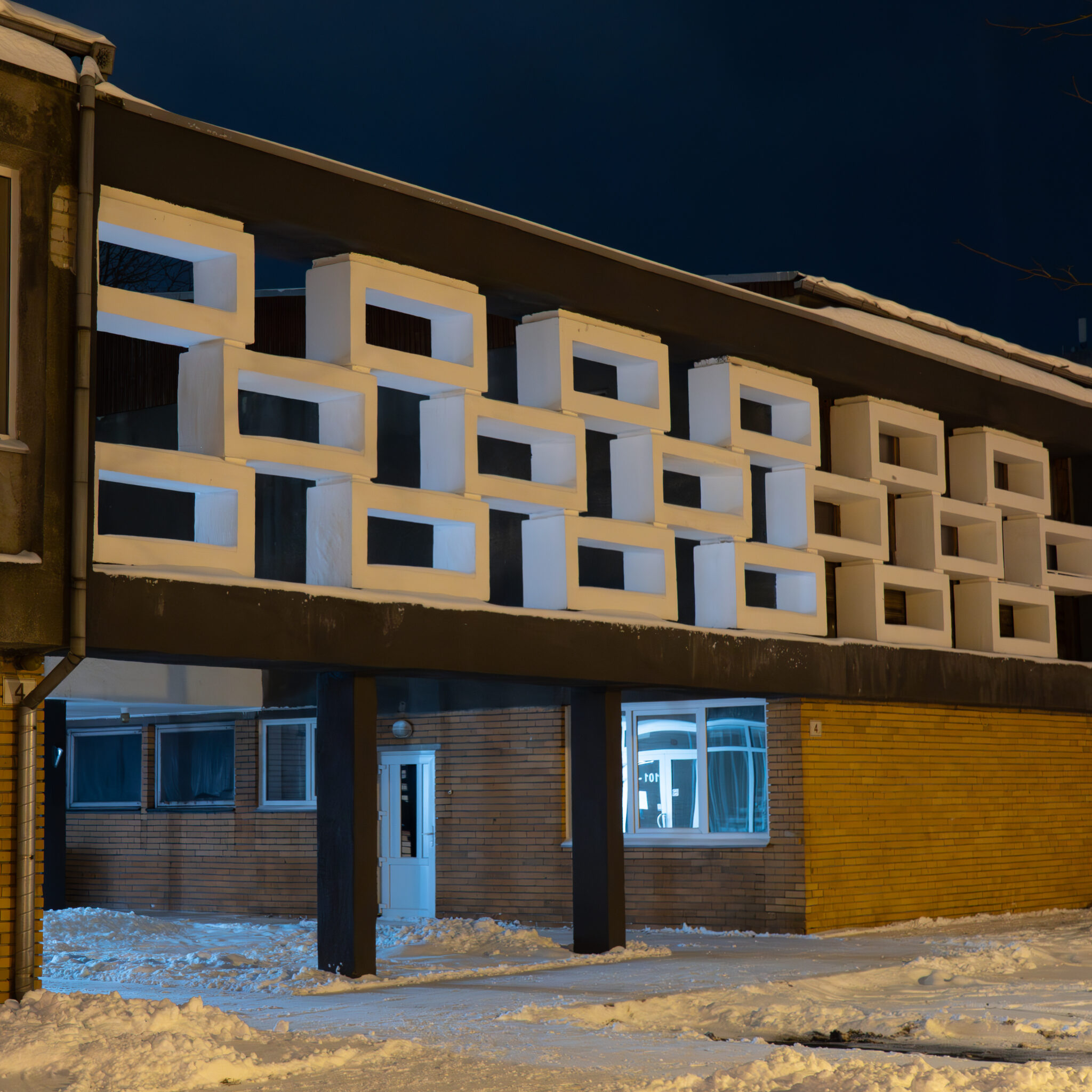 Omanäolise fassaadiga moodne hoone öösel valgustatuna.