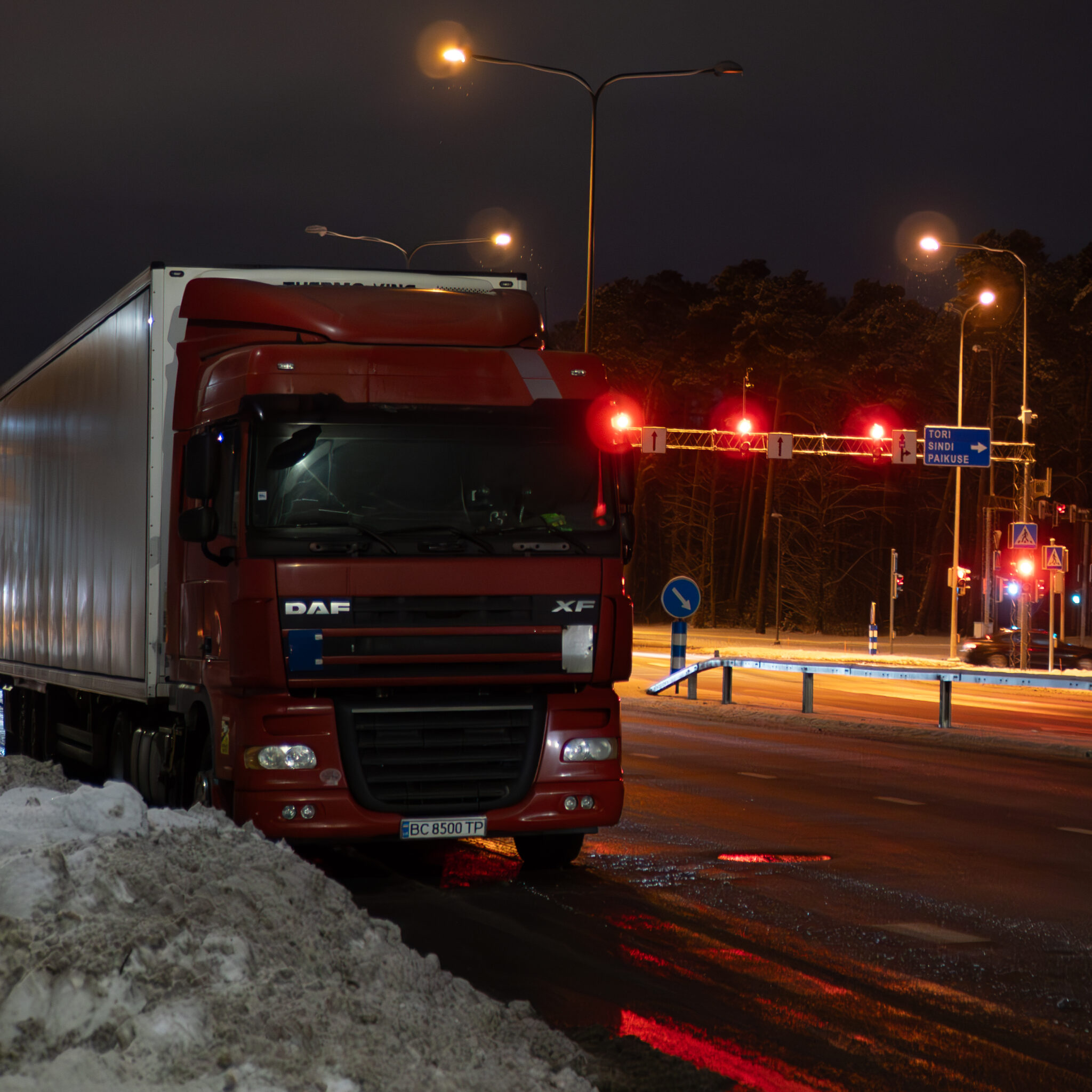 Punane veoauto öisel lumisel teel.