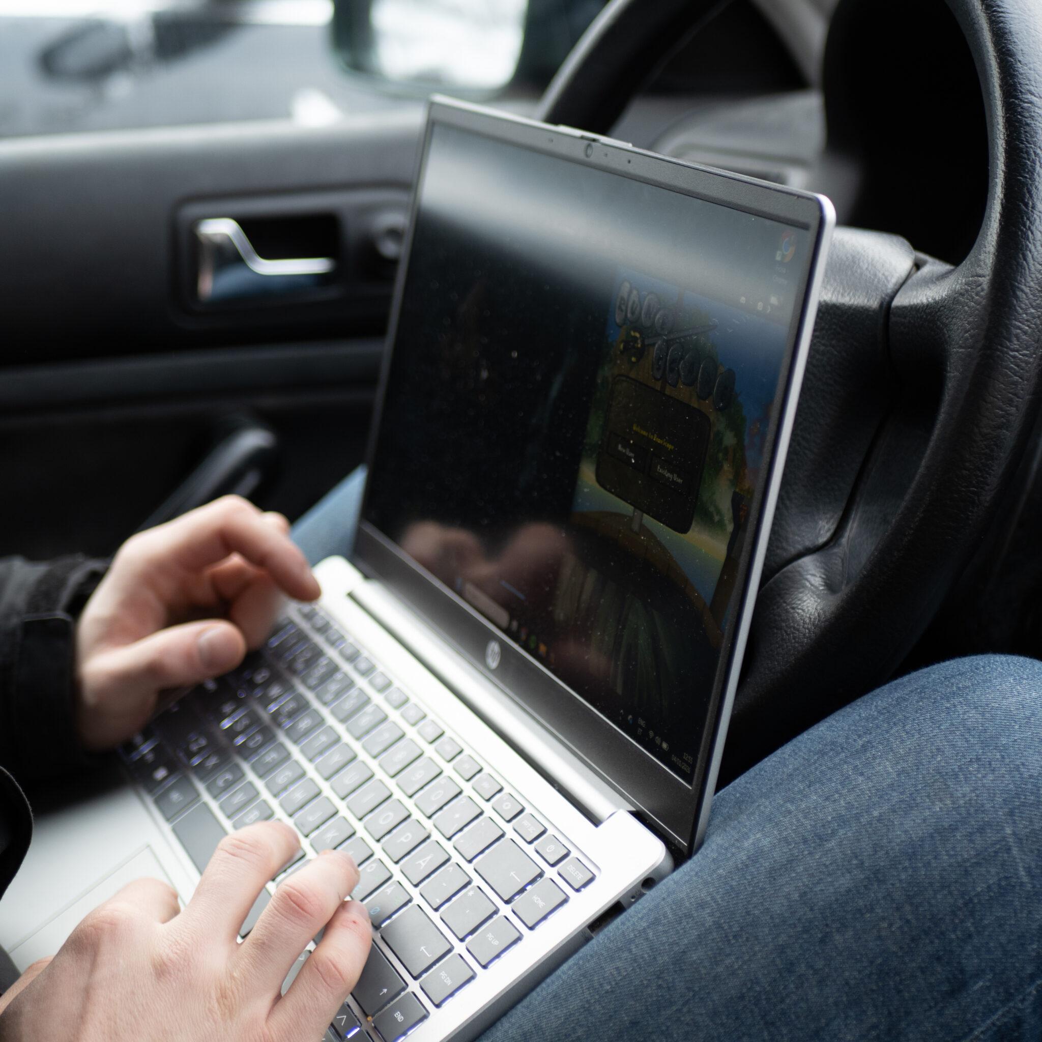 Inimene kasutab autos sülearvutit ja mängib videomängu.