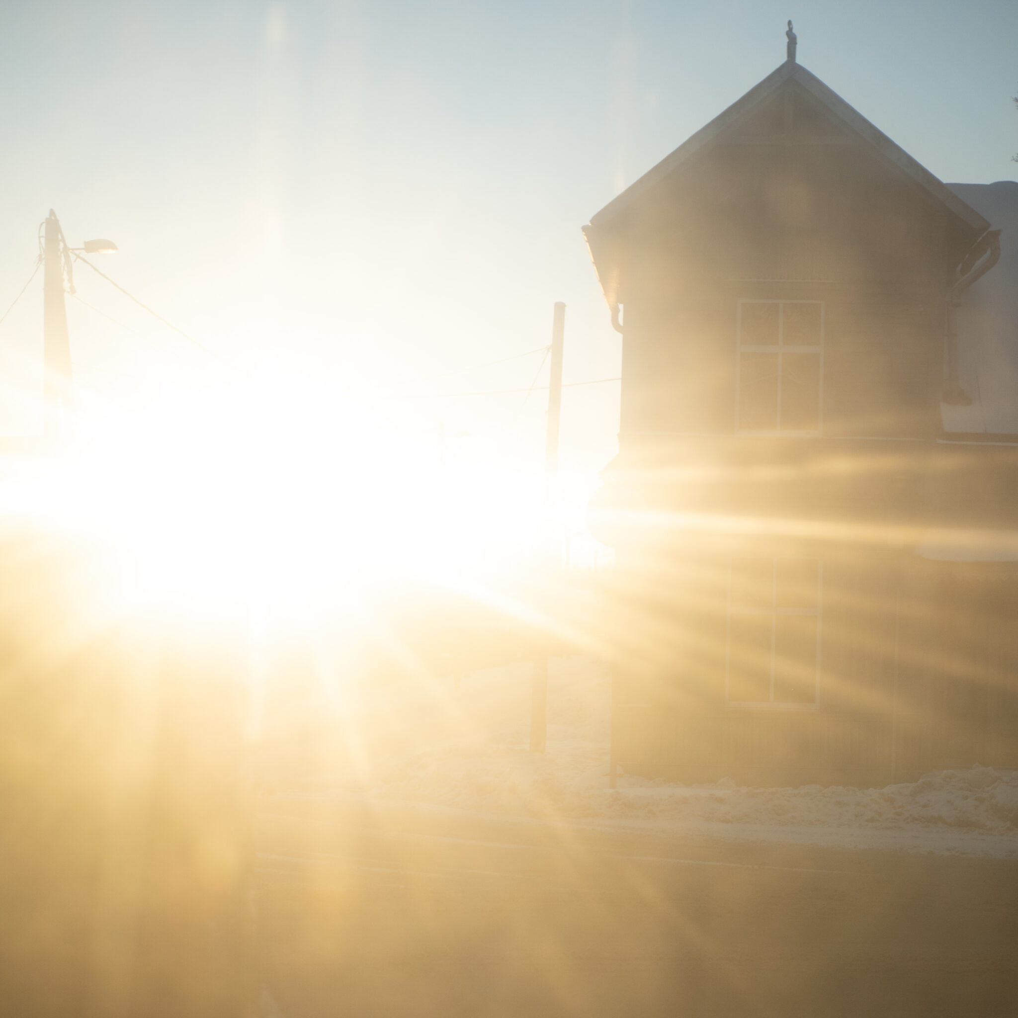 Päikesekiired paistavad läbi puumaja uduse akna.