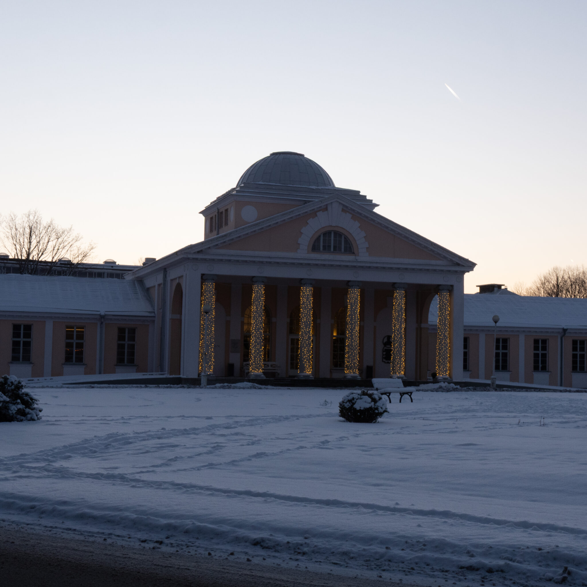 Suursugune sammaste ja kupliga hoone videvikus, kaetud lumega.