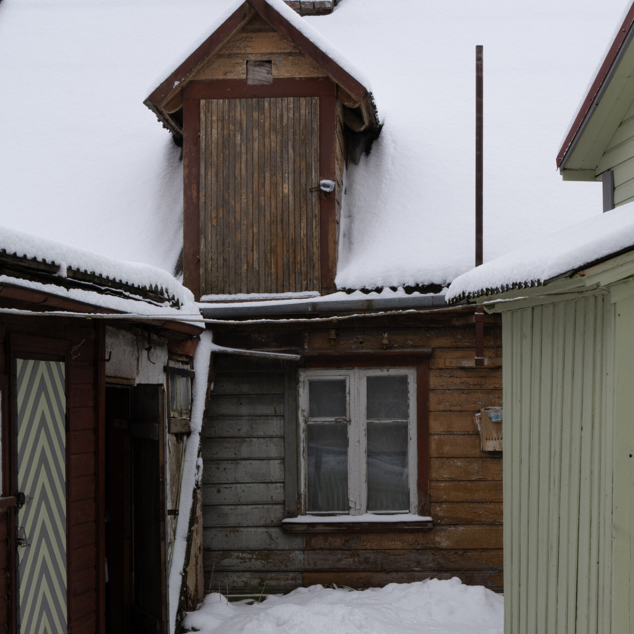 Lumega kaetud pööning ja aken vanas puumajas.