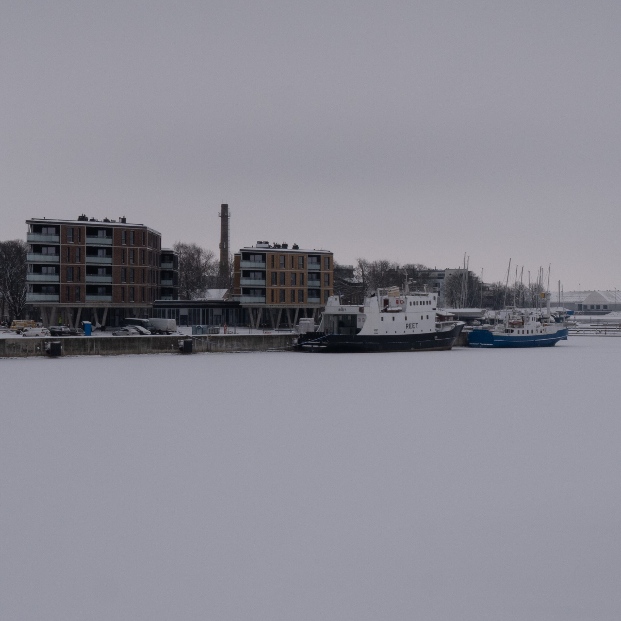 Paadid lumises sadamas, taustal hooned.