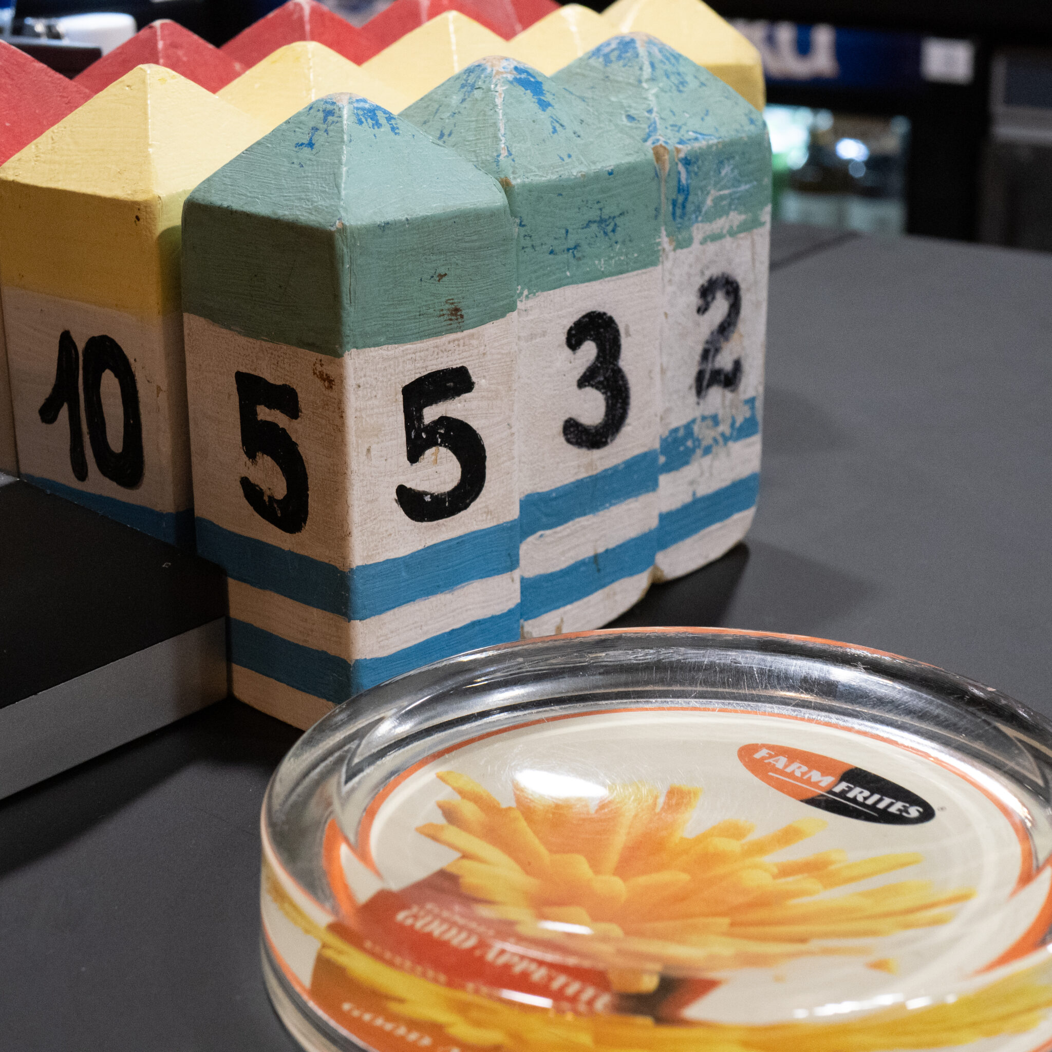 Puitklots numbritega 10, 5, 5, 3, 2 ja klaasist tuhatoos friikartulitega.