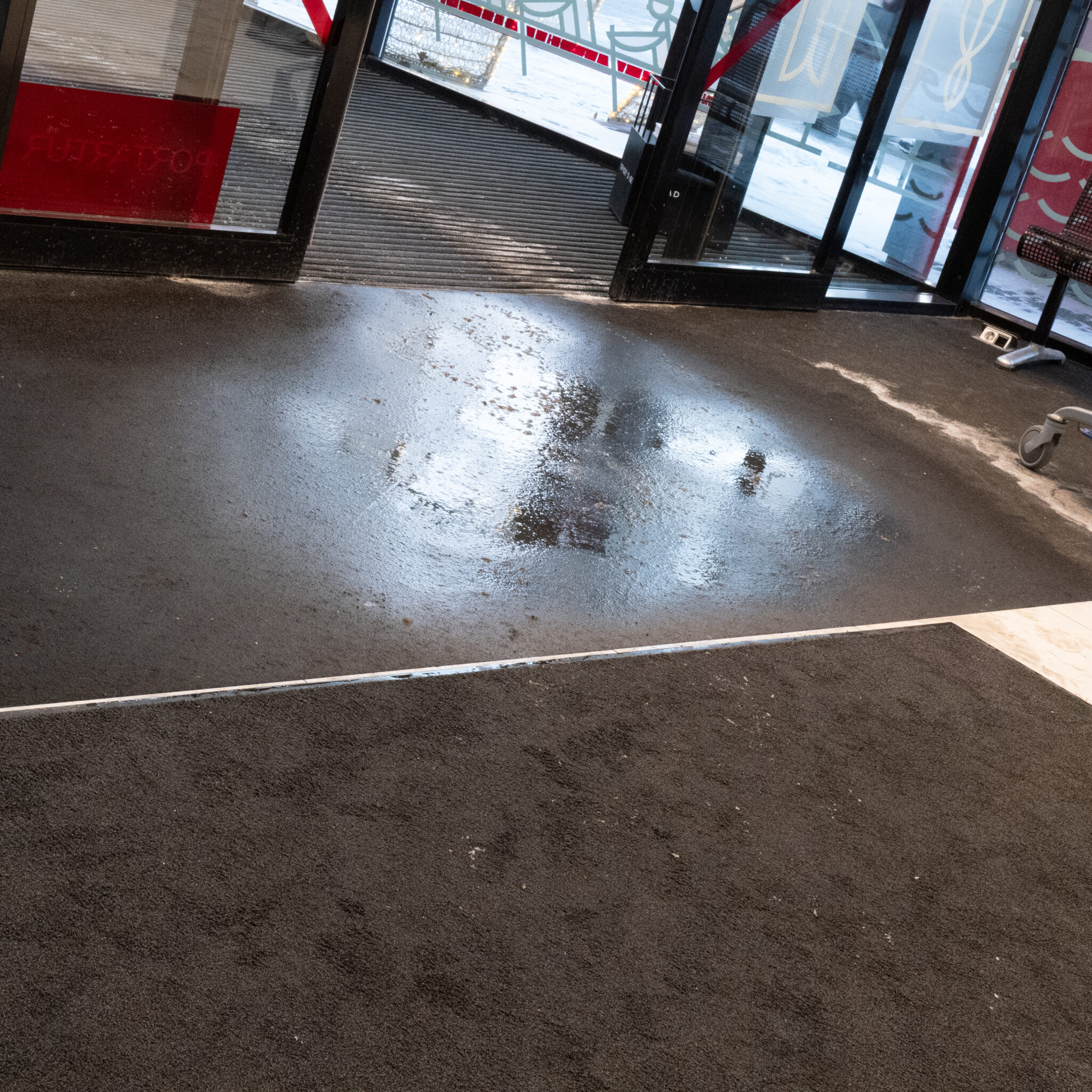 Märg ja peegeldav põrand hoone sissepääsu ees.