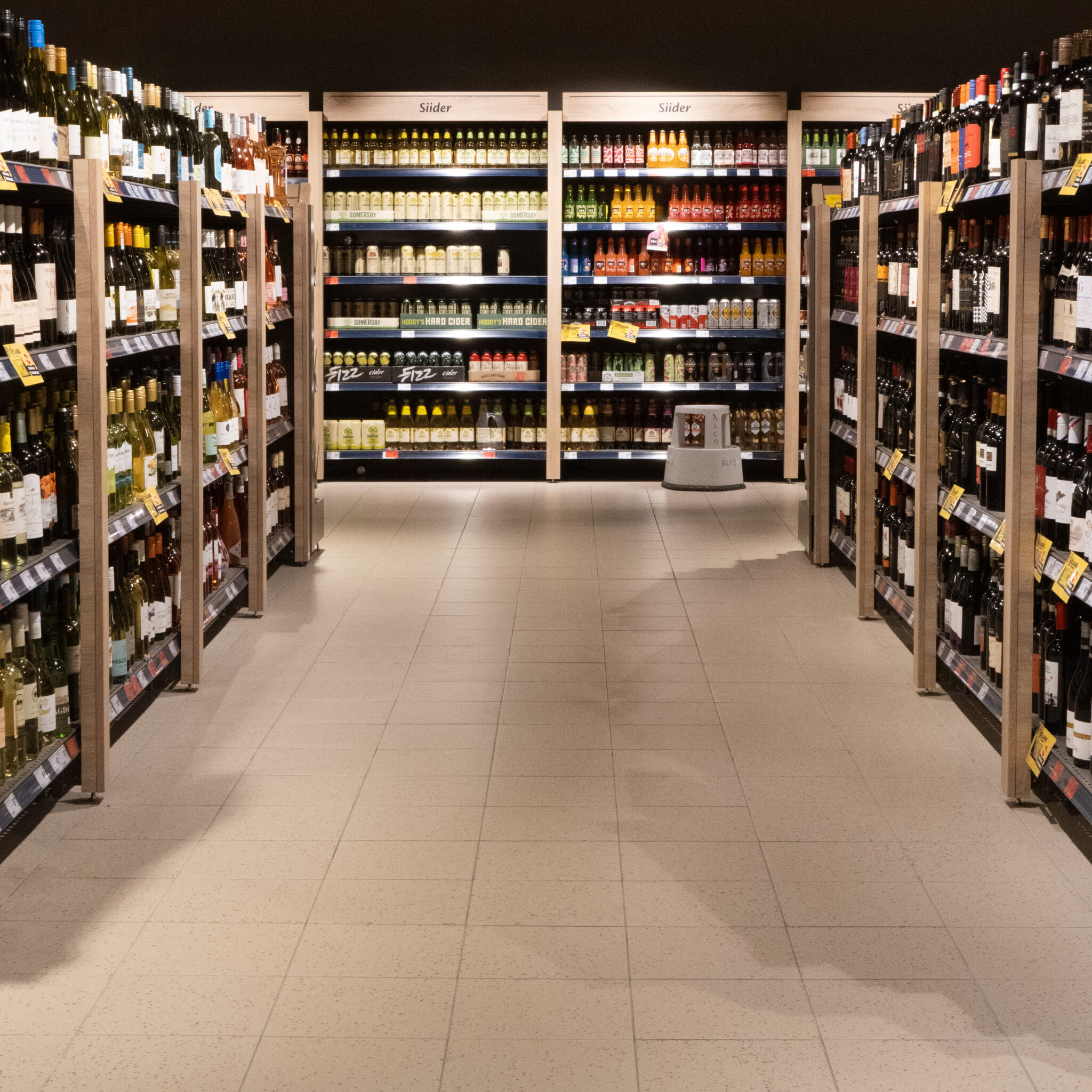 Hästi valgustatud supermarketikäik veini- ja õlleriiulitega.