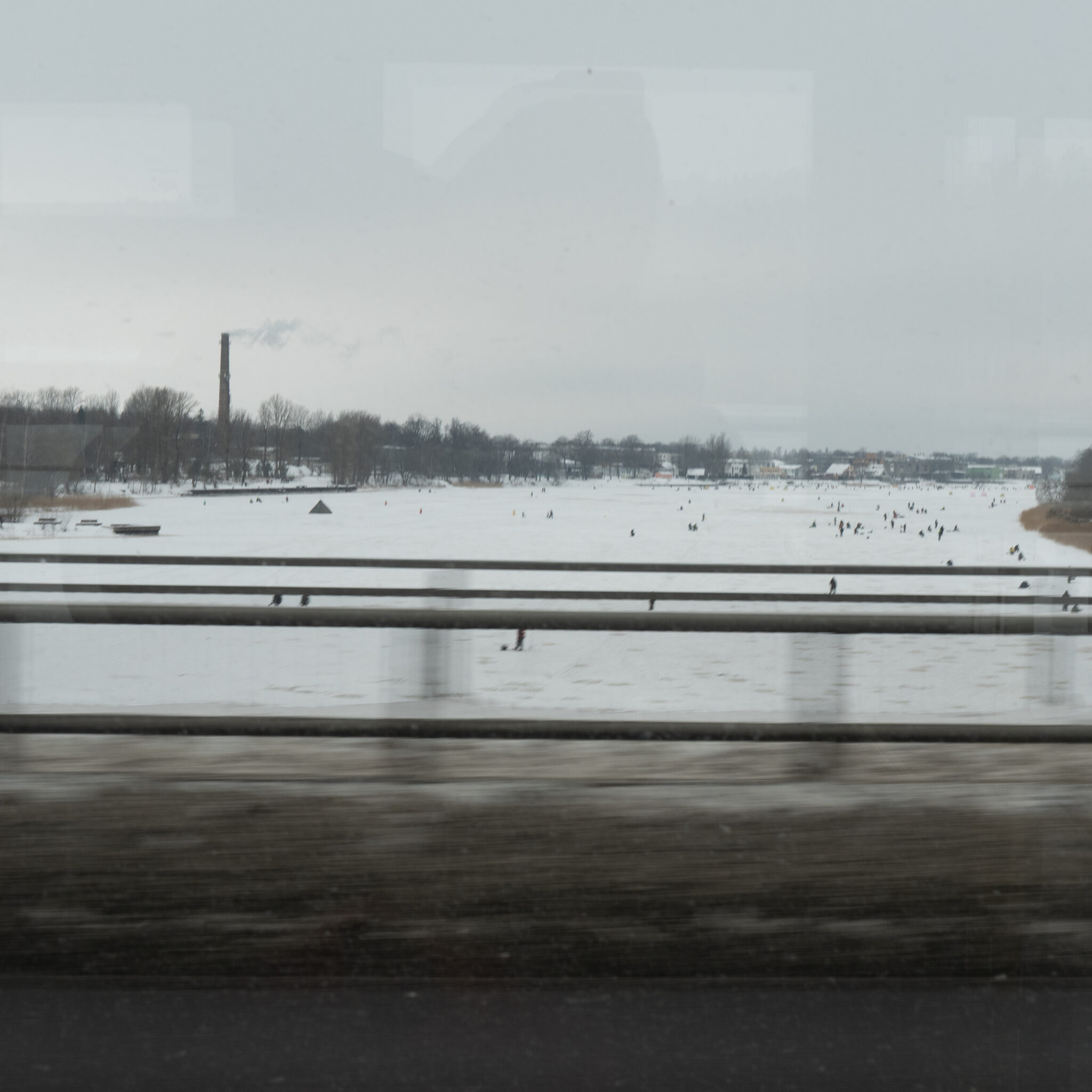 Lumine maastik kauguses korstnaga ja jääl aega veetvate inimestega.