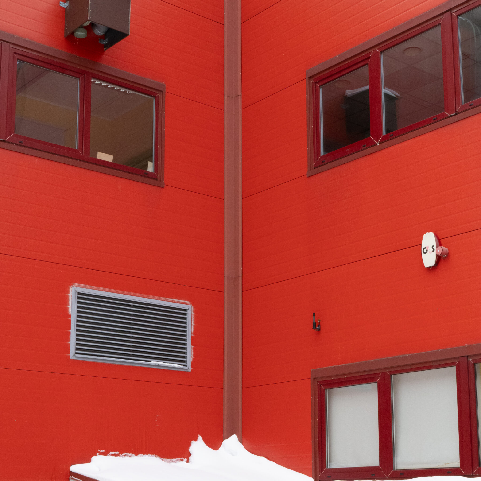 Punane hoone akende ja ventilatsiooniavaga.