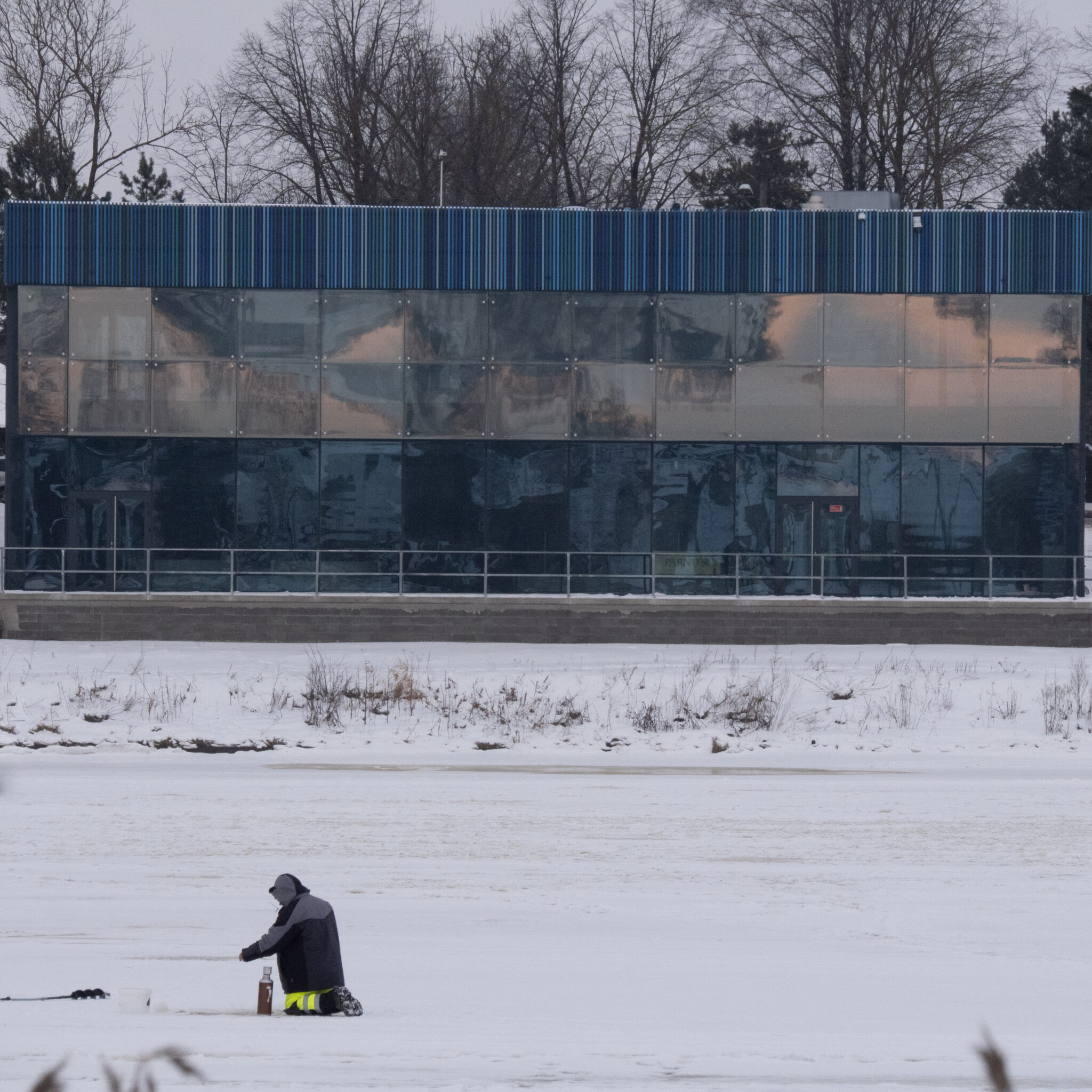 Inimene püüab jäält kala moodsa hoone ees.