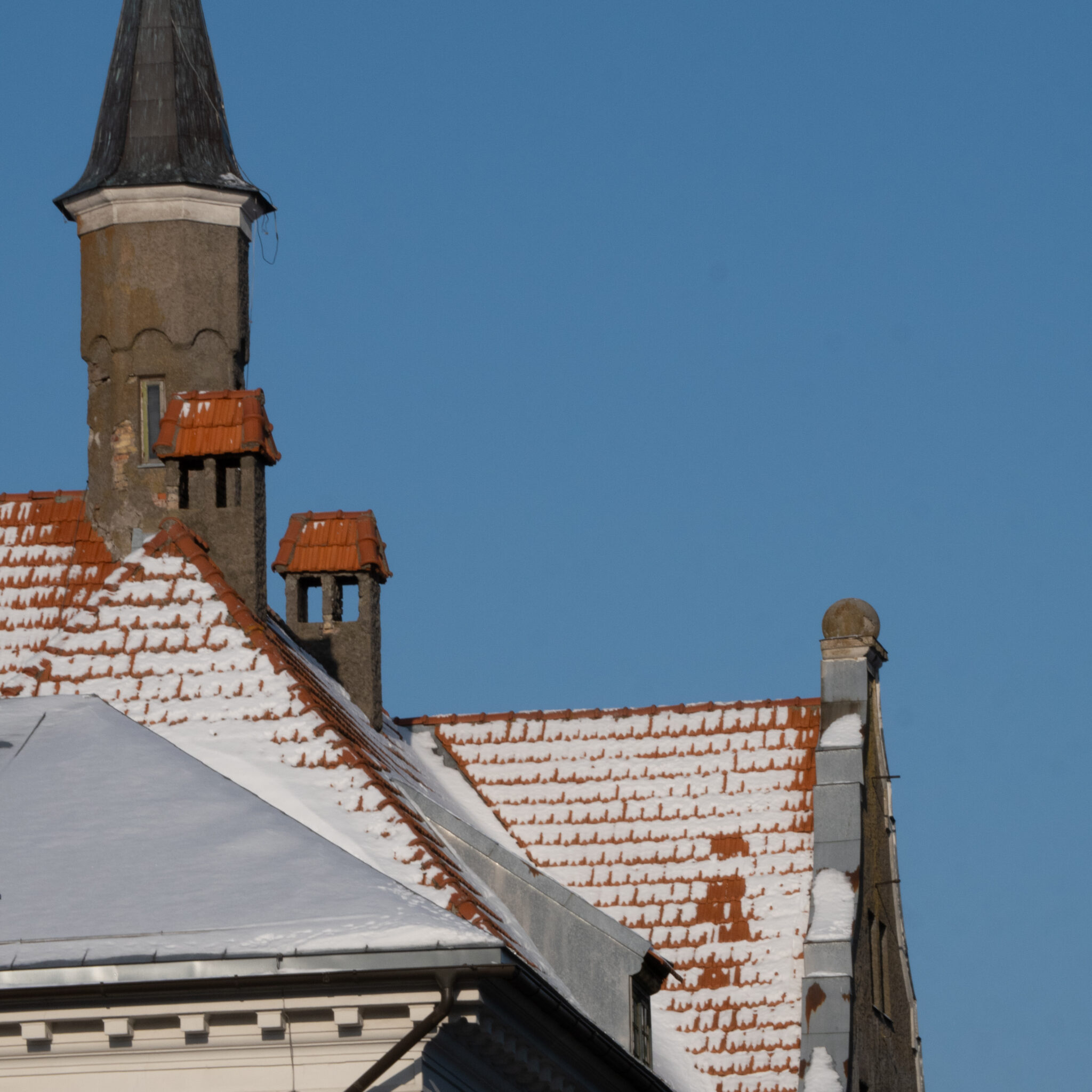 Lumega kaetud katus kõrge torni ja korstnaga.