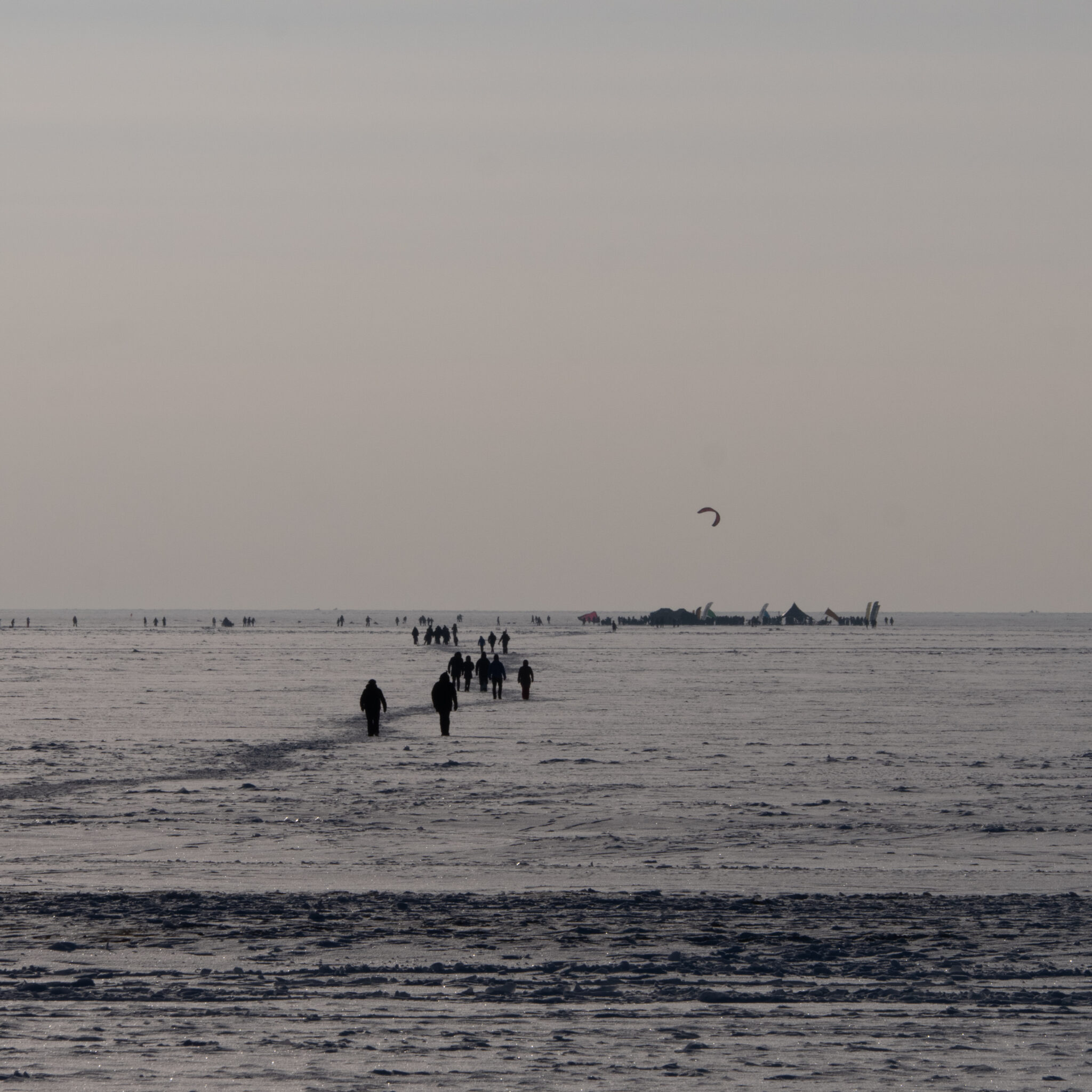 Inimesed kõnnivad lumisel rannal, kauguses lohe.