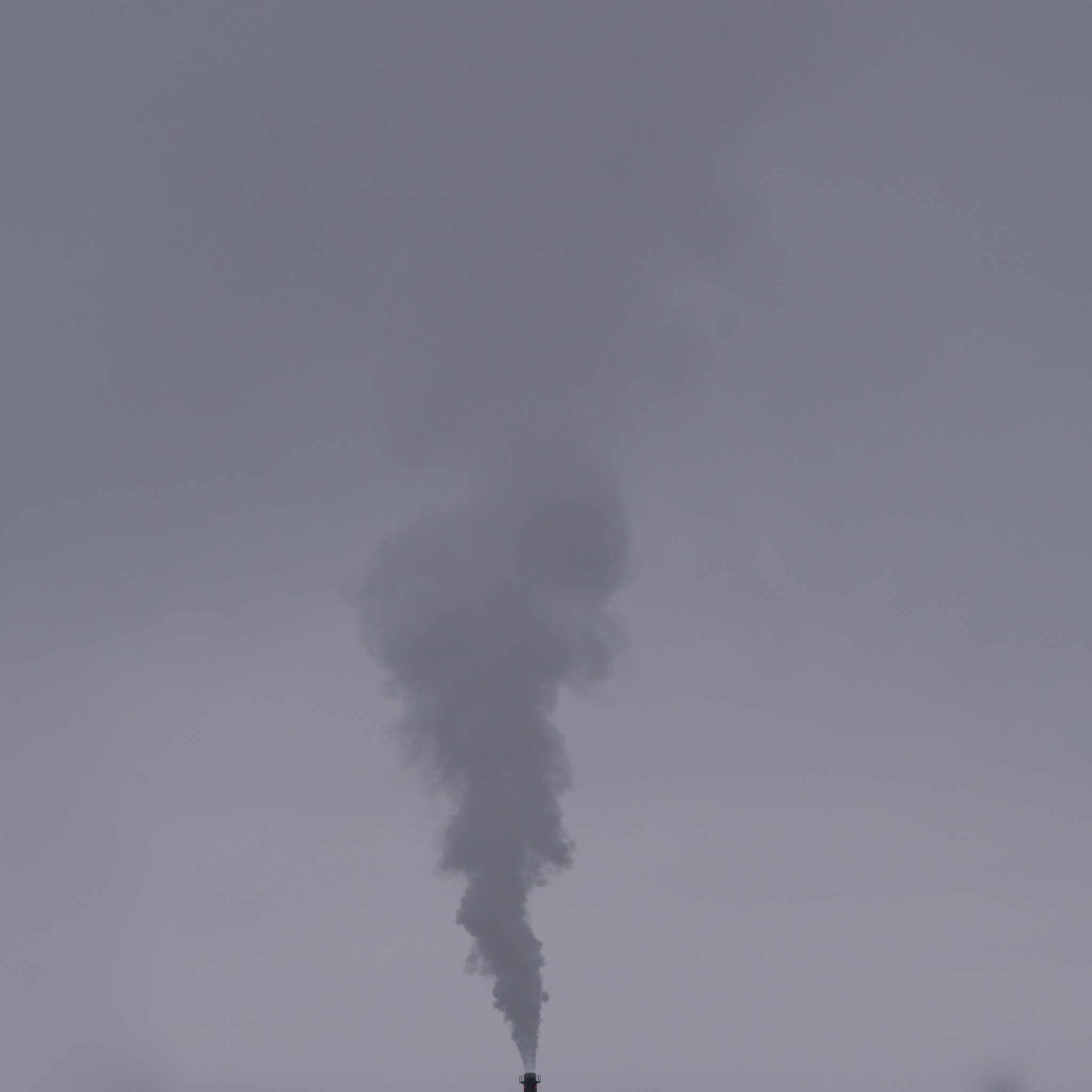 Suitsu paiskav korsten halli taeva taustal.