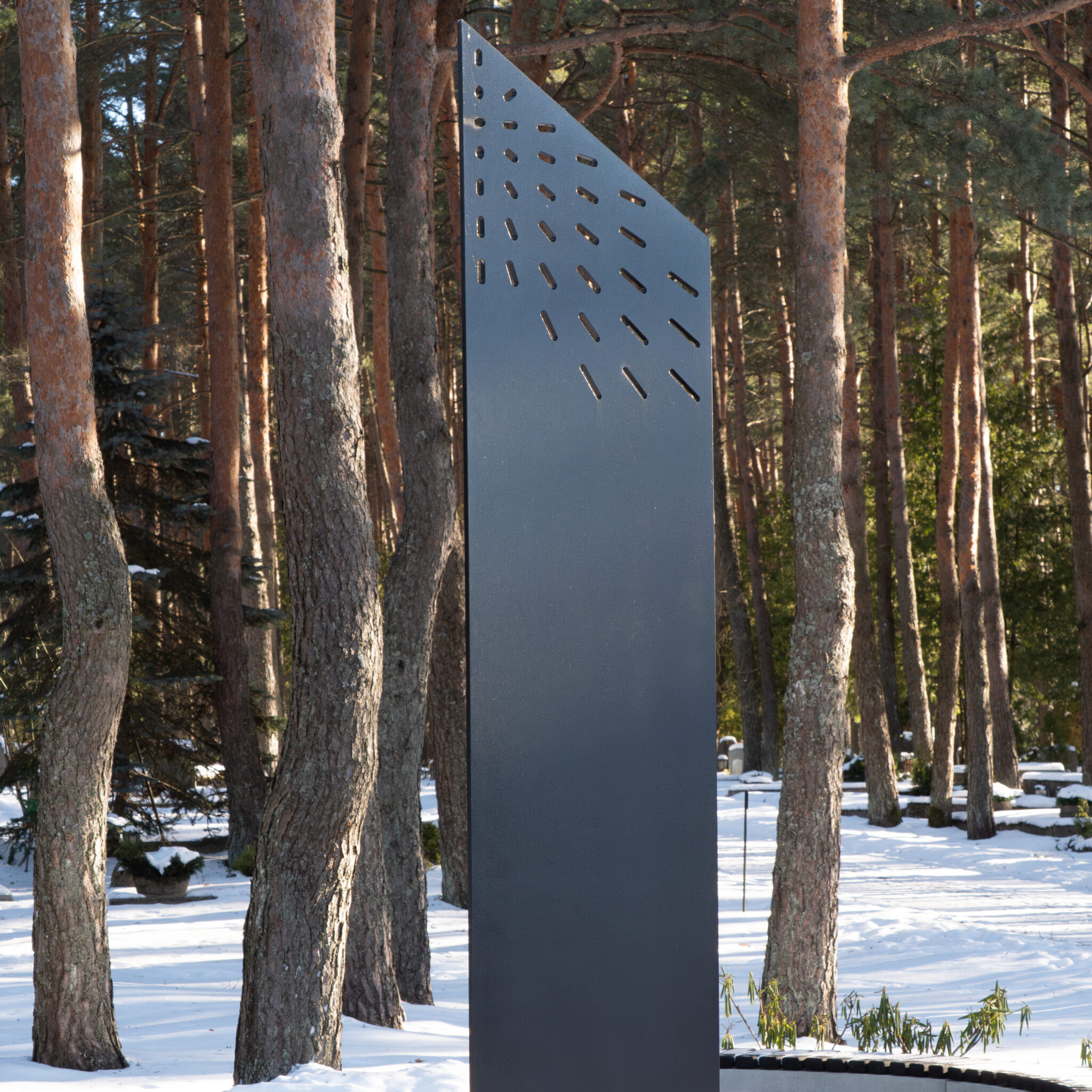 Moodne geomeetriline skulptuur lumises metsas.