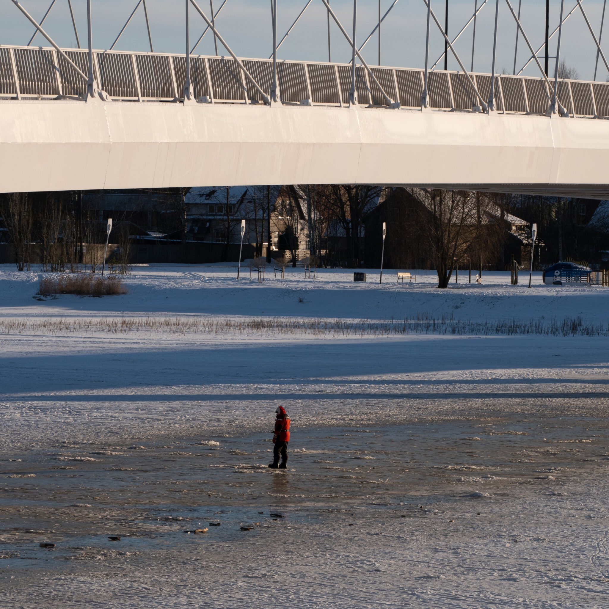 Punases jopes inimene seisab silla all jäätunud jõel.