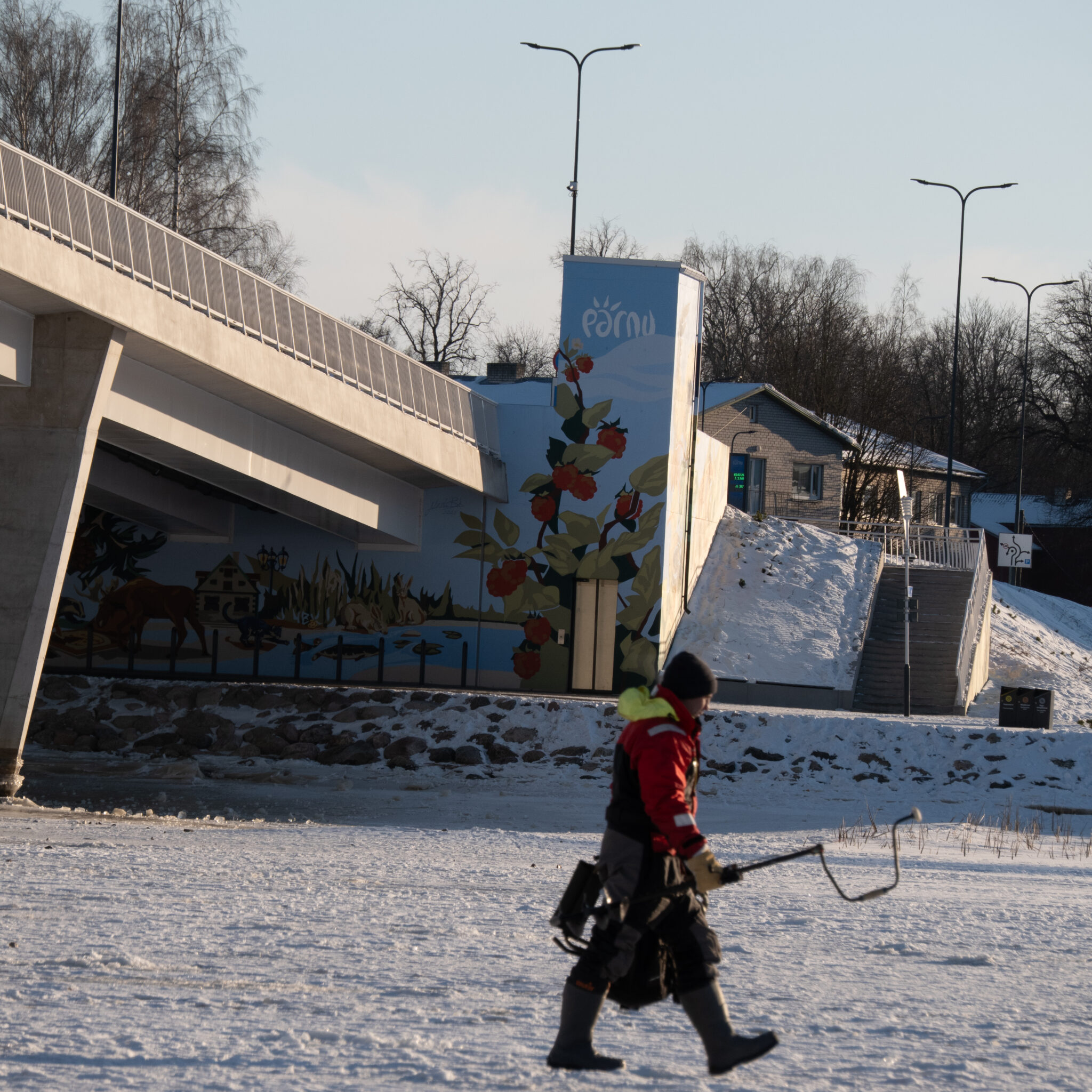 Talveriietes inimene kõnnib seinamaalinguga silla juurest mööda.
