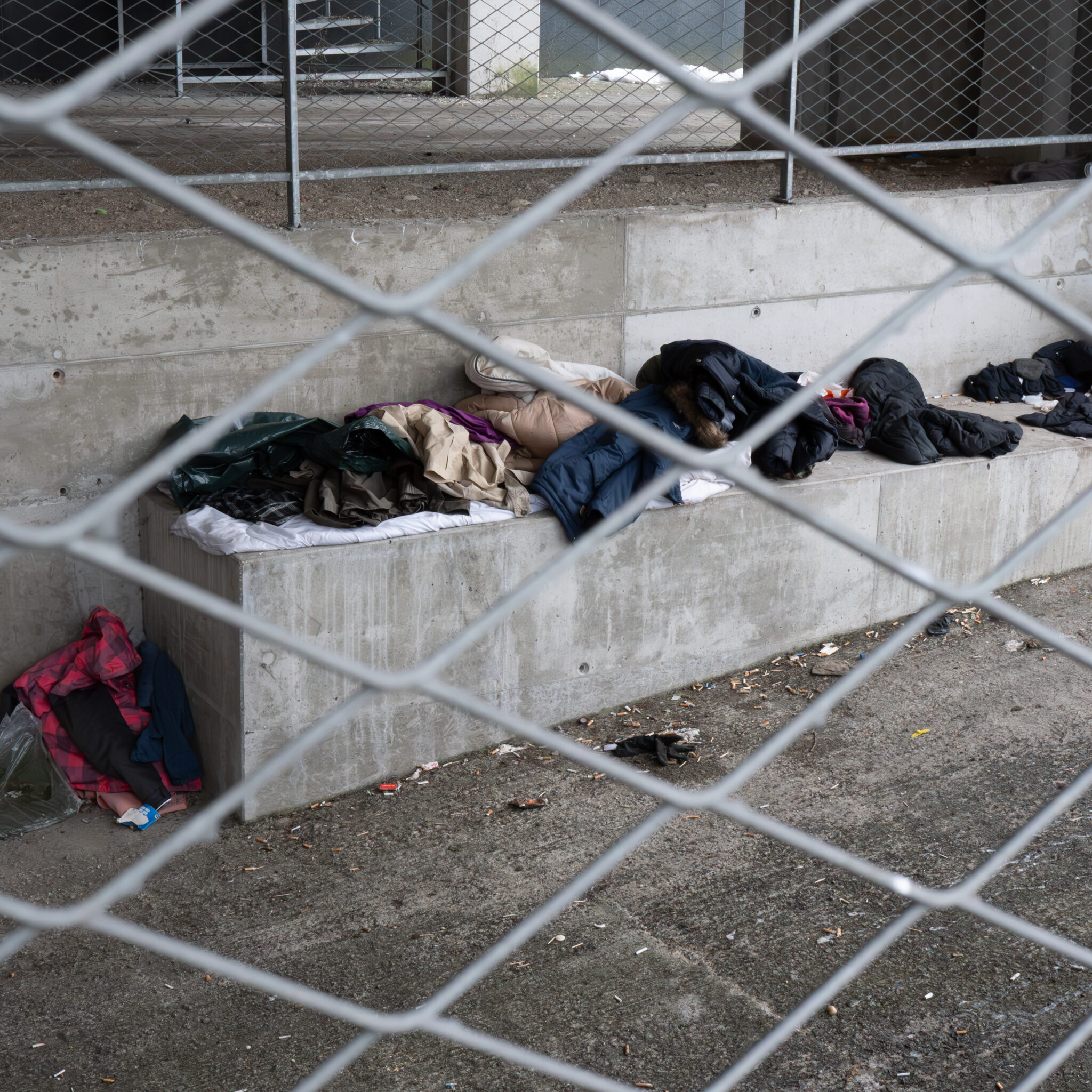 Kodutute asjad pingil, nähtuna läbi võrkaia.