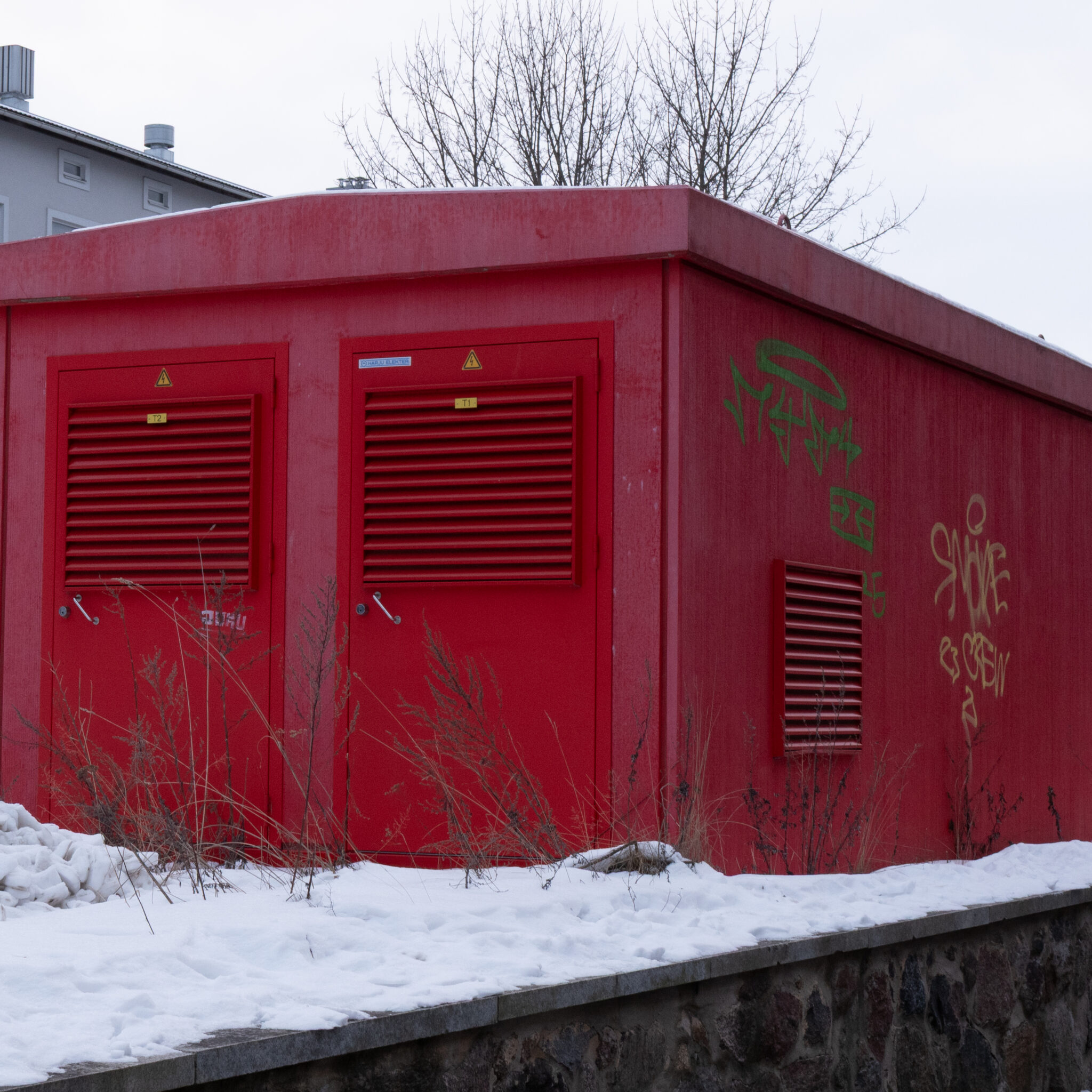 Punane grafitiga tehnokapp lumisel maapinnal.