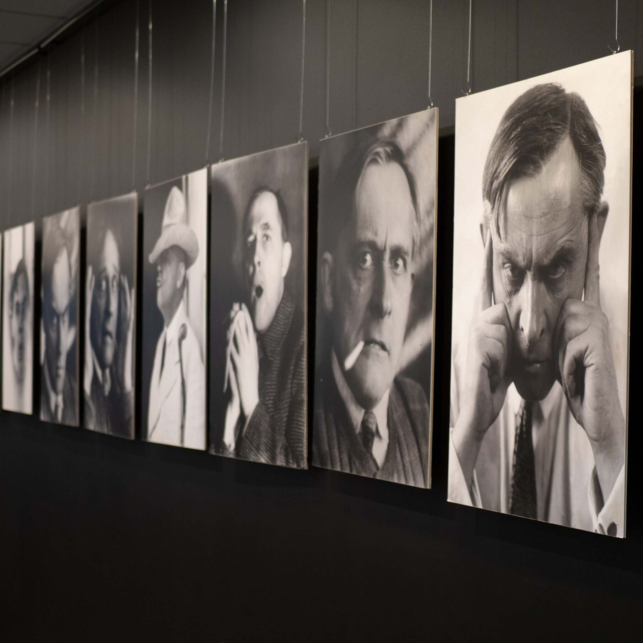 Rida mustvalgeid portreesid ripub seinal.