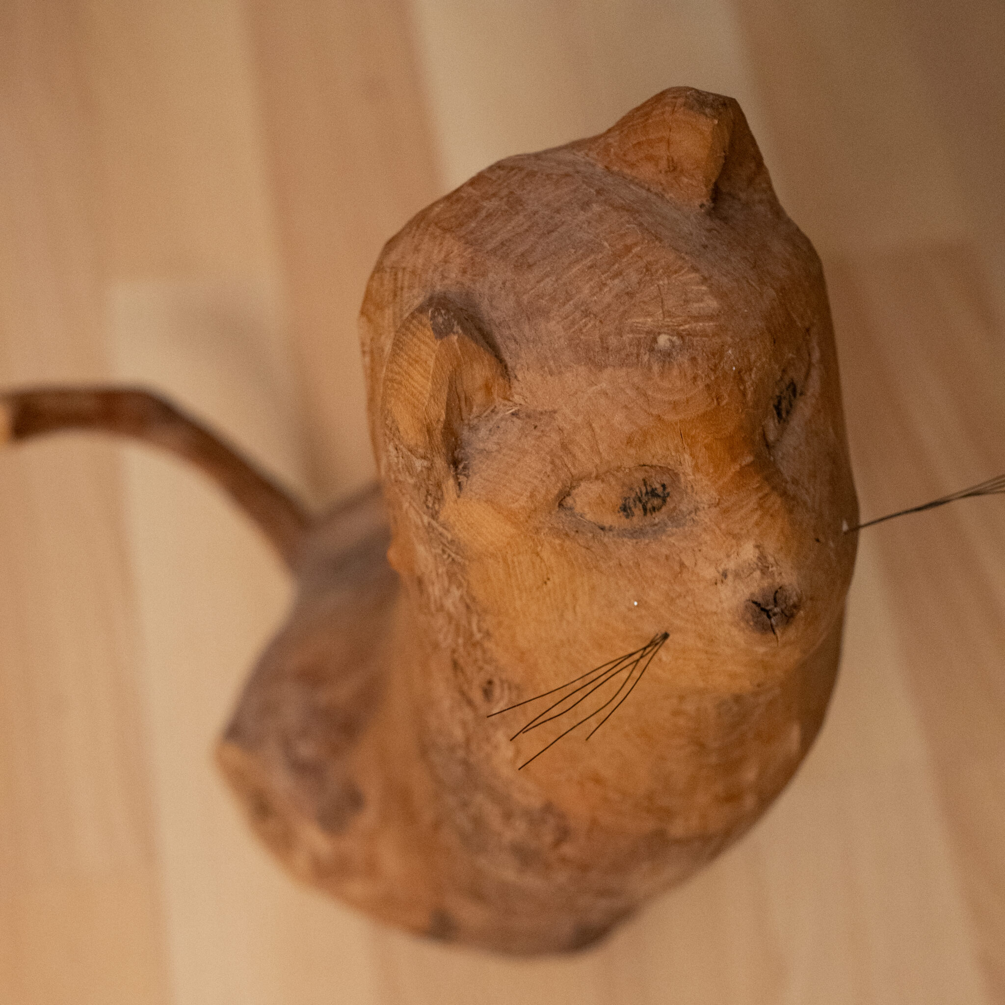 Puidust nikerdatud kassimänguasi realistliku saba ja vurrudega.