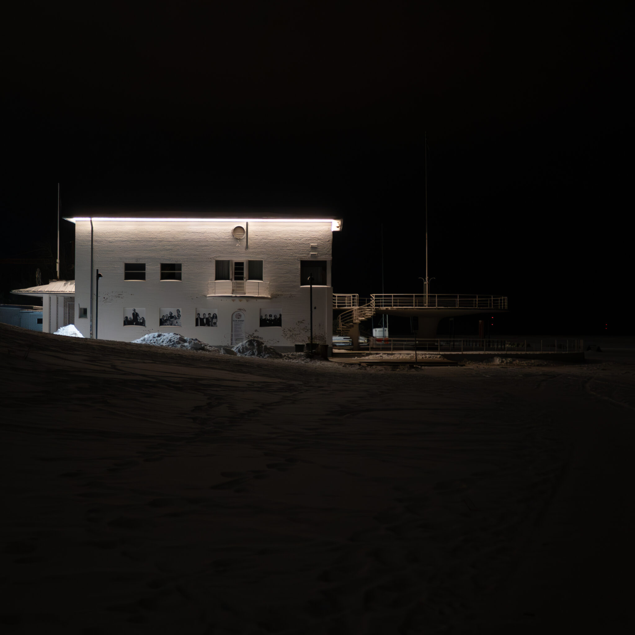 Valge akende ja rõduga hoone öösel valgustatuna.