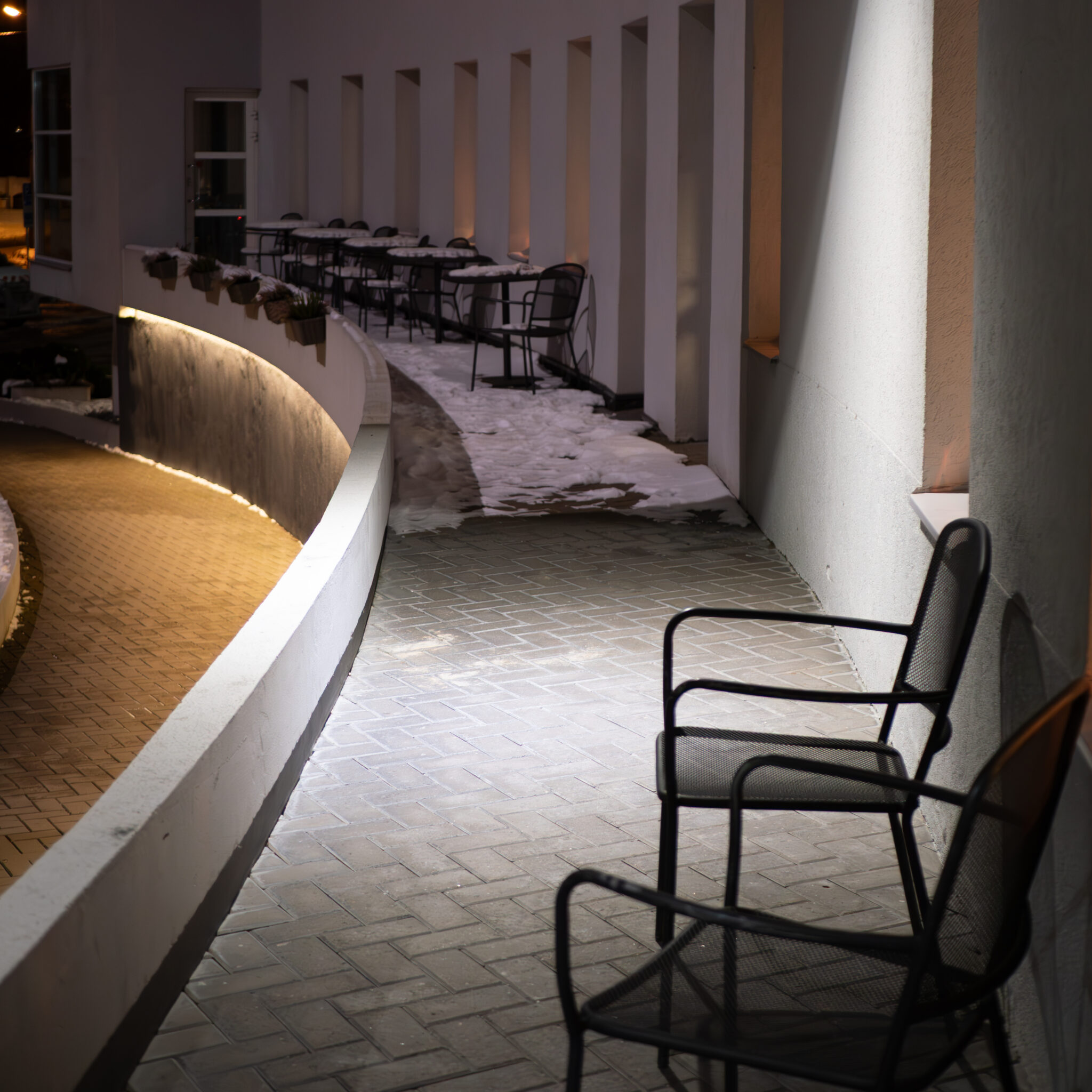 Hubane laudade ja toolidega väliala öösel valgustatuna.