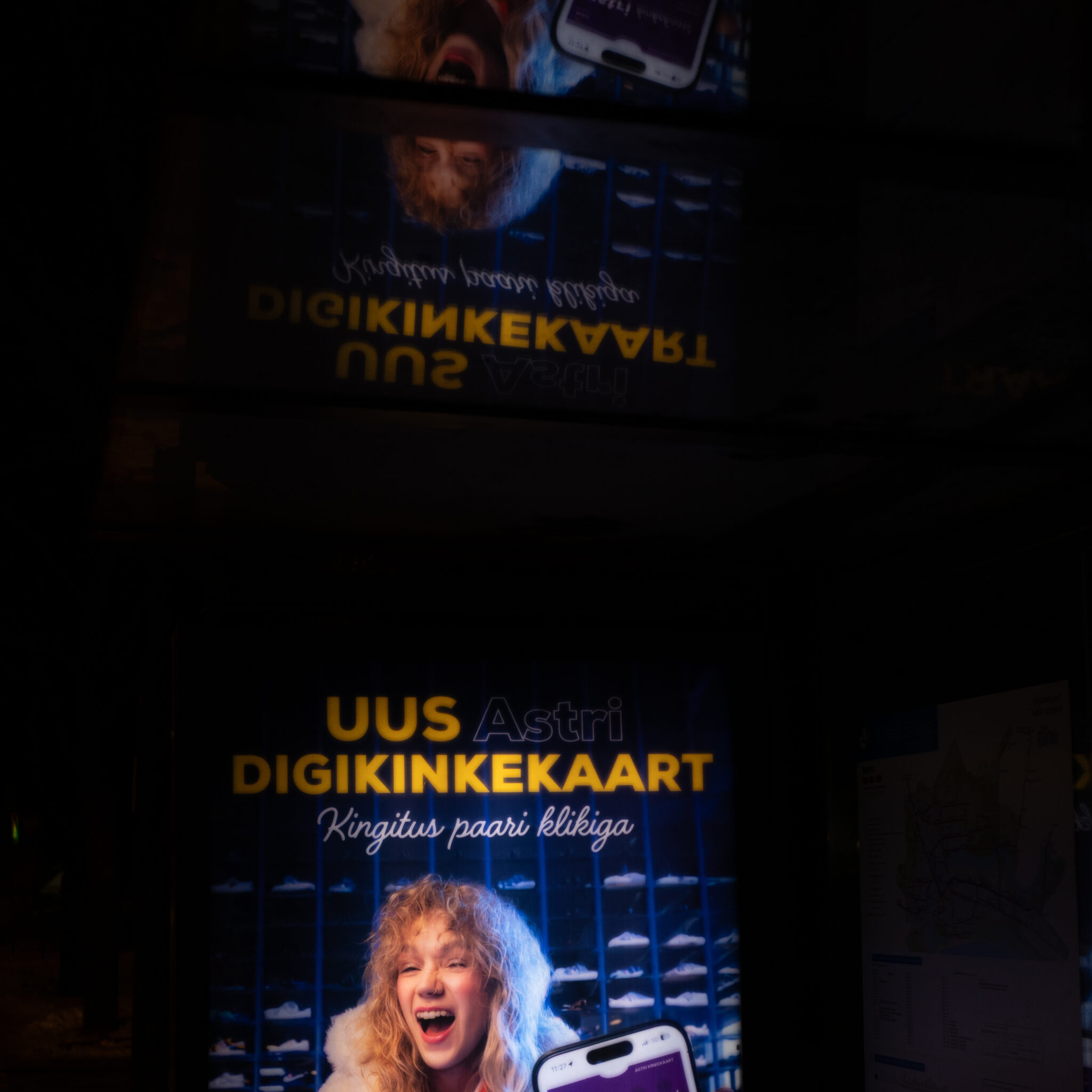 Naine naerab digipiletiteenuse sildi ees.