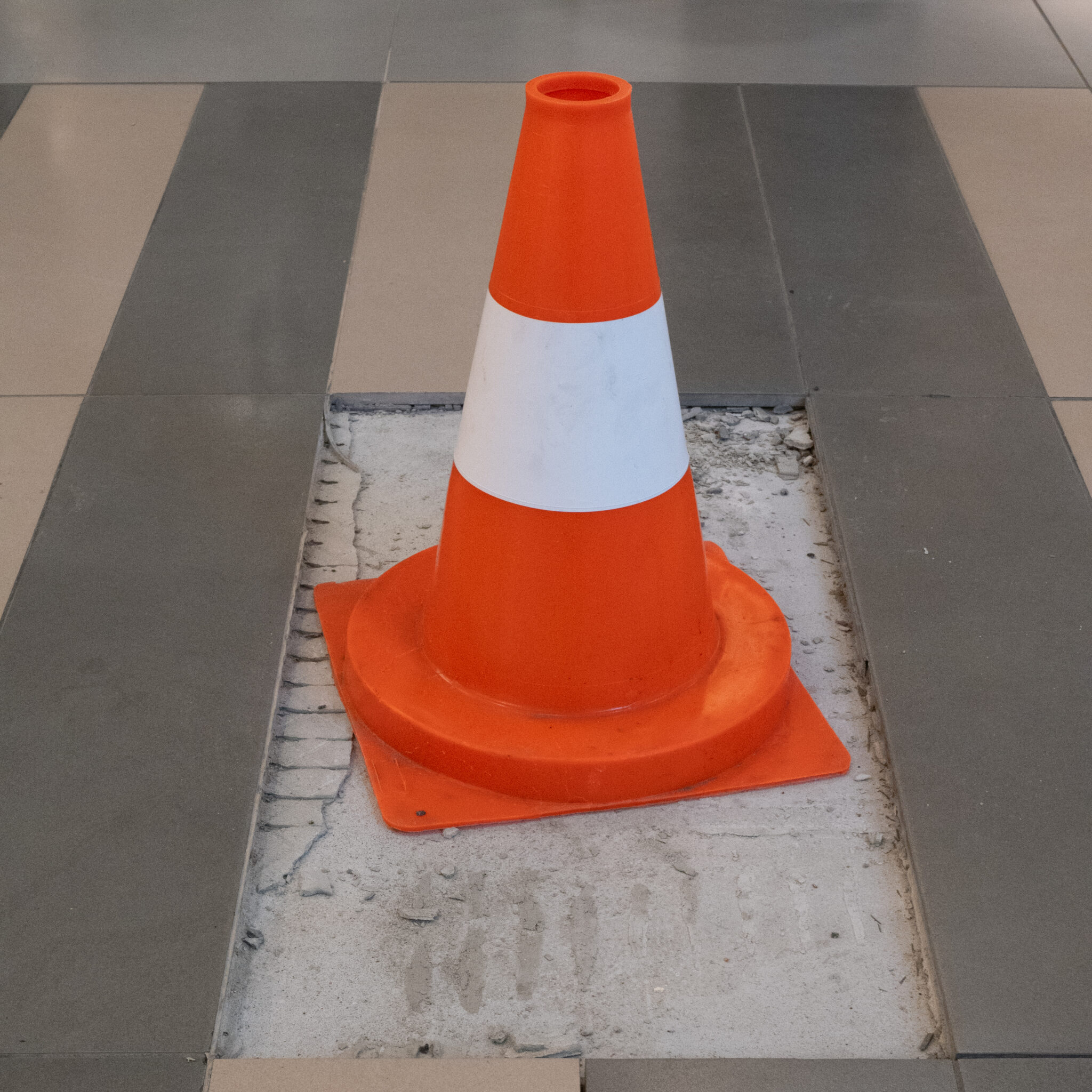 Oranžvalge liikluskoonus plaaditud põrandal.