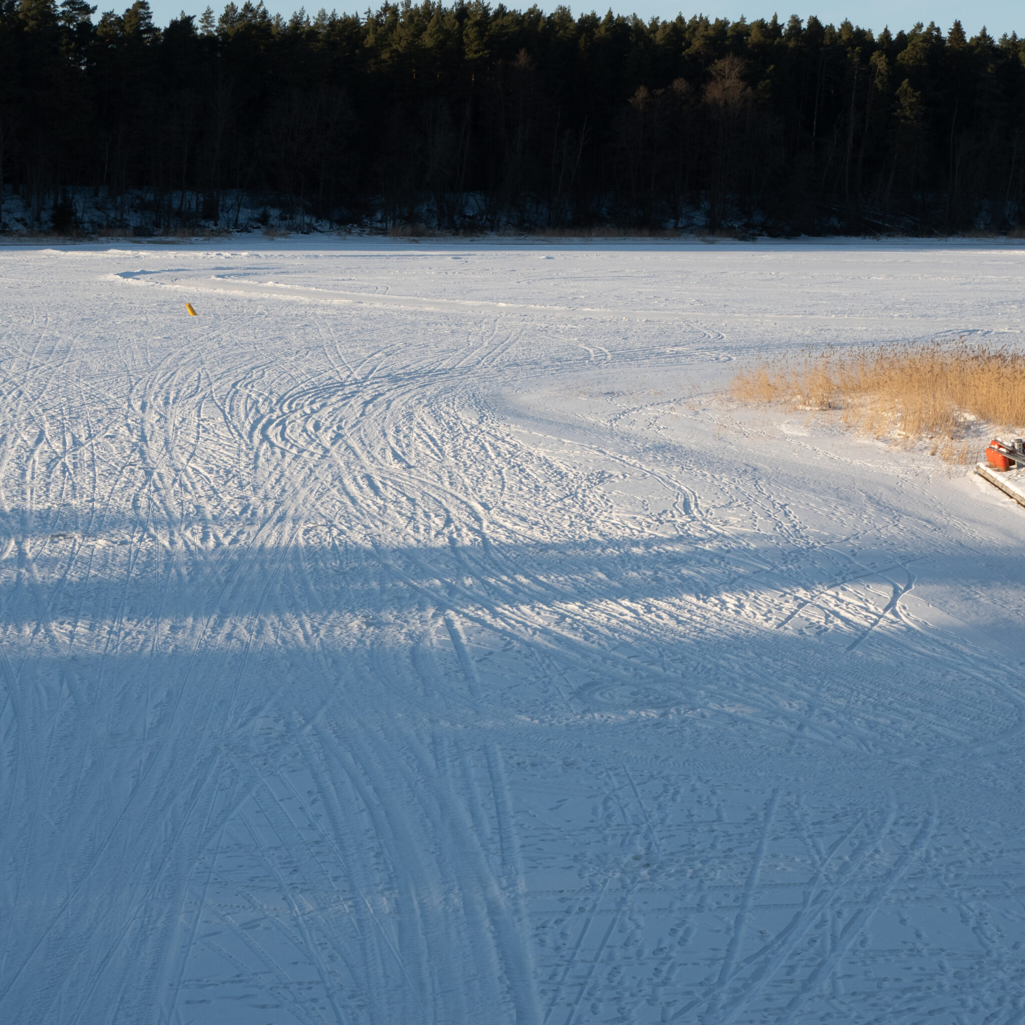 Jäätunud järv rehviradade ja kollase märgistusega.