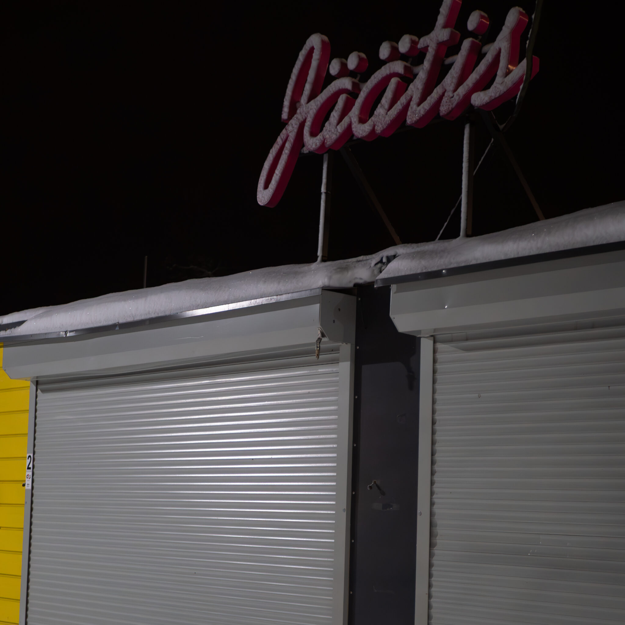 Lumega kaetud Jäätise silt kollasel hoonel.