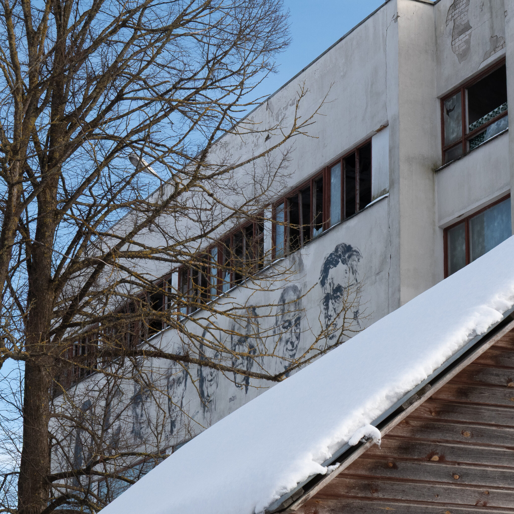 Lumise katusega hoone, esiplaanil puu.